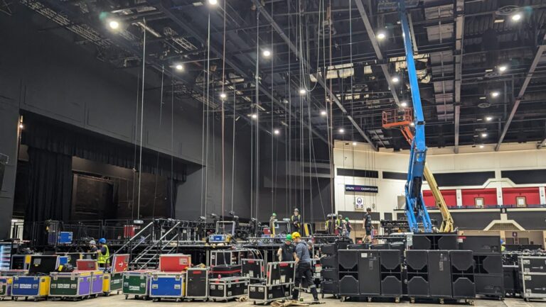 Event riggers are hanging equipment from a truss for a live event